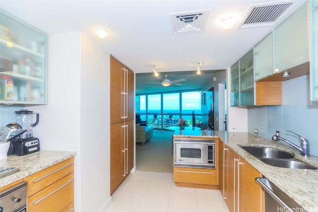 kitchen with ceiling fan, stainless steel appliances, light stone countertops, and sink