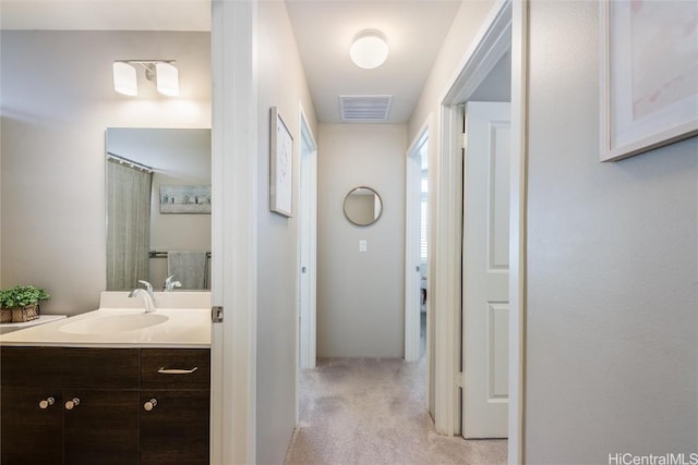 corridor featuring light carpet and sink