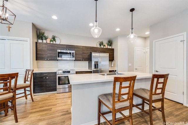 kitchen featuring stainless steel appliances, decorative light fixtures, sink, and dark brown cabinets