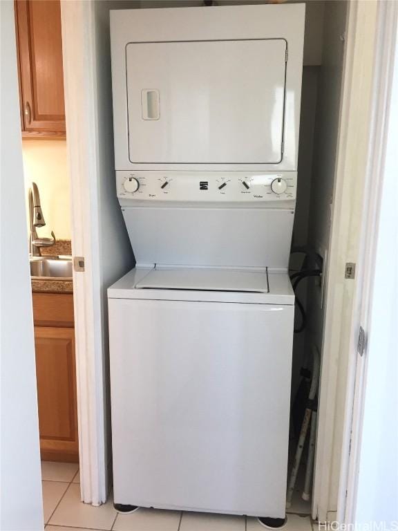 laundry room featuring stacked washer / dryer, sink, and light tile patterned floors