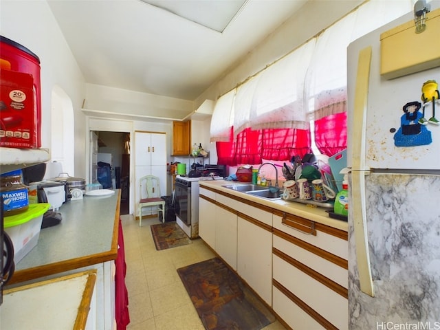 kitchen with white cabinetry, sink, and white range with gas stovetop