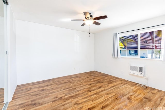 empty room featuring wood-type flooring, an AC wall unit, and ceiling fan