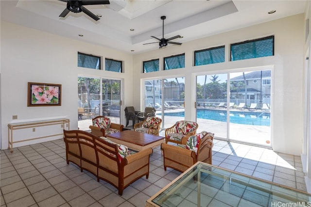 tiled living room with a tray ceiling, ceiling fan, and a towering ceiling