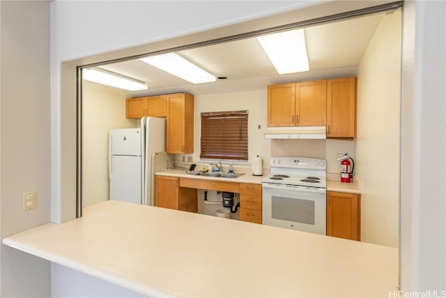 kitchen with white appliances, kitchen peninsula, and sink