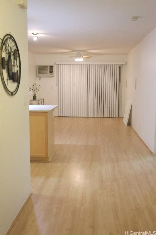 unfurnished room with a wall mounted AC, ceiling fan, and light hardwood / wood-style flooring