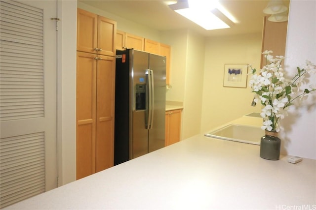 kitchen with sink, stainless steel fridge, and light brown cabinetry