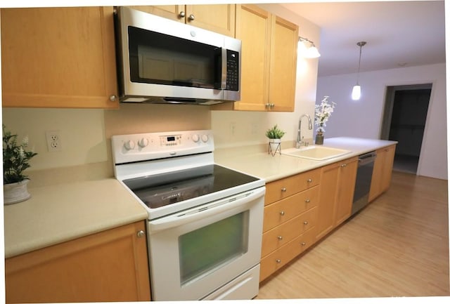 kitchen with appliances with stainless steel finishes, light brown cabinetry, decorative light fixtures, sink, and light wood-type flooring