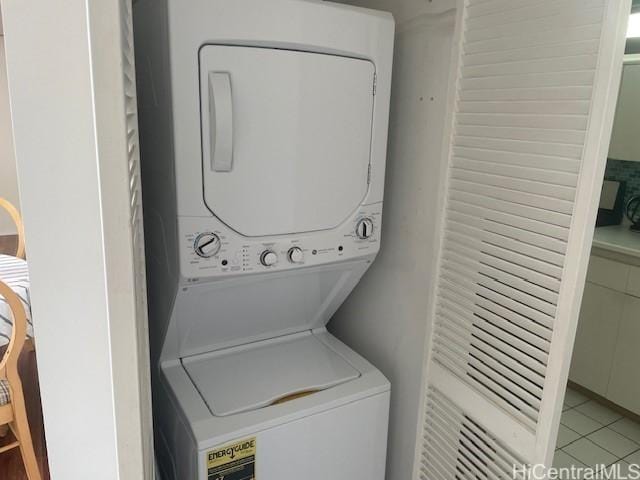 washroom with stacked washer / drying machine and light tile patterned flooring