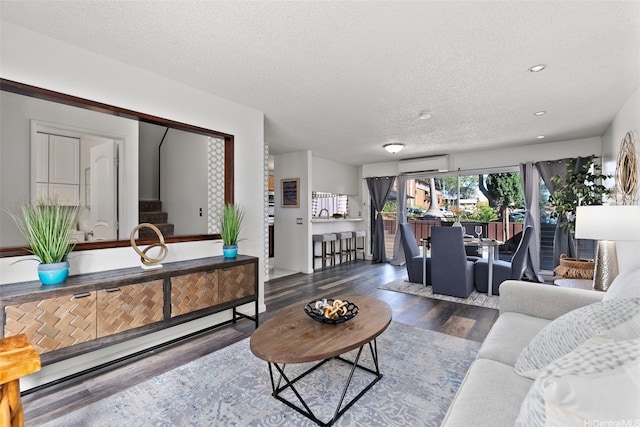 living area featuring a textured ceiling, a wall unit AC, recessed lighting, stairway, and wood finished floors