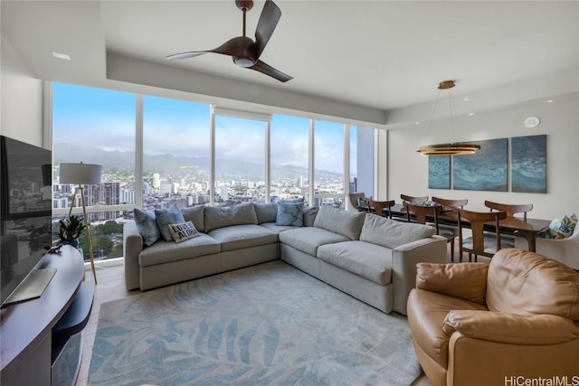 living room featuring ceiling fan, a wall of windows, light hardwood / wood-style floors, and a healthy amount of sunlight