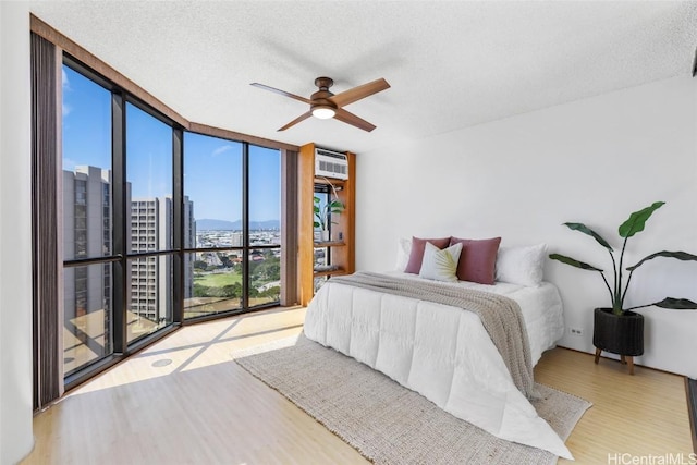 bedroom featuring ceiling fan, floor to ceiling windows, a textured ceiling, and light wood-type flooring