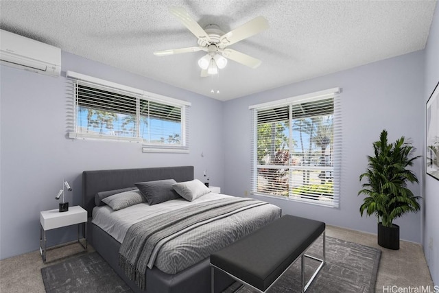 carpeted bedroom featuring ceiling fan, a wall mounted AC, and a textured ceiling