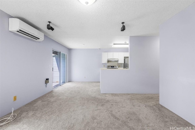 unfurnished living room with light carpet, an AC wall unit, and a textured ceiling