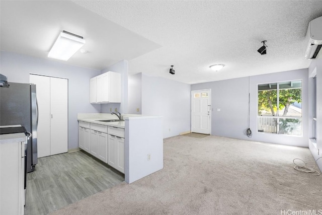 kitchen featuring white cabinetry, sink, stainless steel fridge, and a textured ceiling