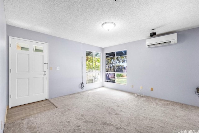 spare room with light carpet, an AC wall unit, and a textured ceiling