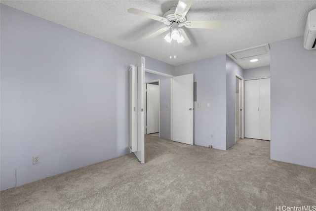 unfurnished bedroom with ceiling fan, a wall unit AC, light carpet, and a textured ceiling