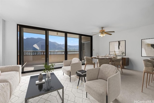 carpeted living room featuring expansive windows, a mountain view, and ceiling fan