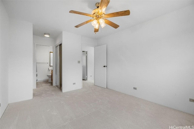 unfurnished bedroom featuring ceiling fan, light carpet, and ensuite bath