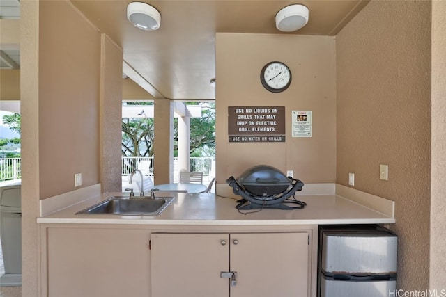 kitchen featuring white cabinetry, refrigerator, and sink