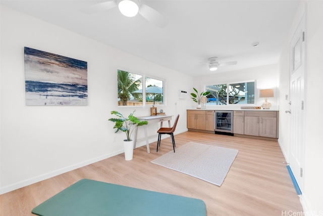 bar with a healthy amount of sunlight, beverage cooler, light brown cabinetry, and light hardwood / wood-style floors