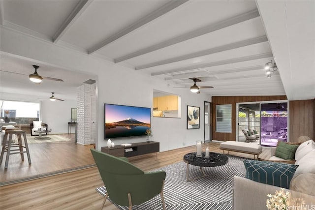 living room featuring beamed ceiling, a wealth of natural light, and light hardwood / wood-style floors