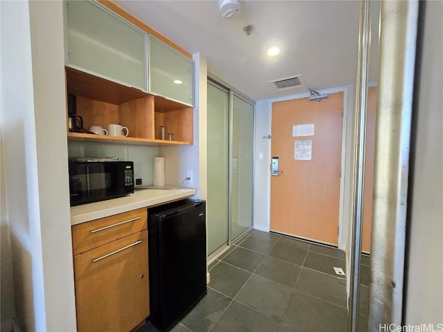 kitchen featuring refrigerator and dark tile patterned flooring