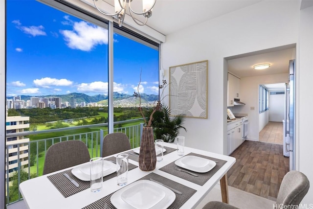 dining space with wood-type flooring, a mountain view, and a notable chandelier