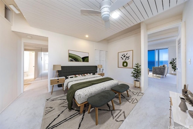 bedroom featuring light colored carpet, wooden ceiling, ceiling fan, and a water view