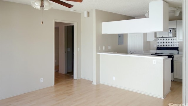 kitchen featuring light wood-type flooring, electric panel, kitchen peninsula, electric stove, and white cabinets