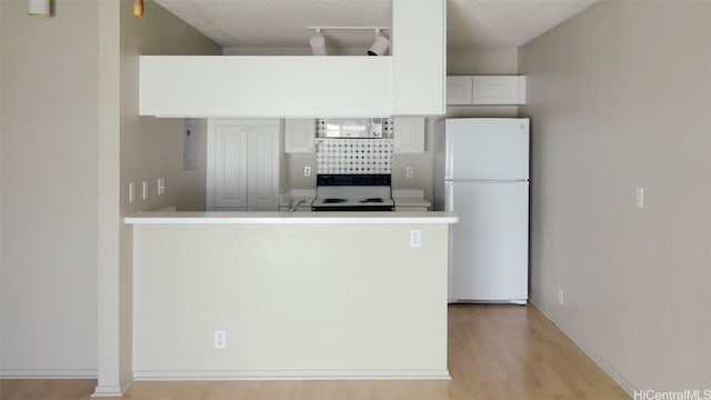 kitchen featuring electric stove, kitchen peninsula, white cabinets, and white refrigerator