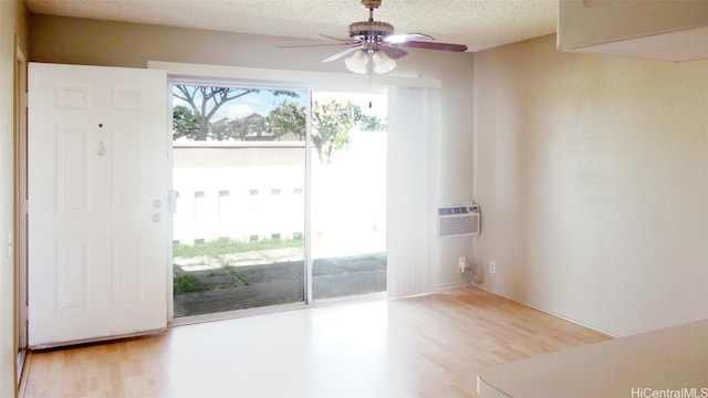 entryway featuring a wall mounted air conditioner, light hardwood / wood-style floors, a textured ceiling, and ceiling fan