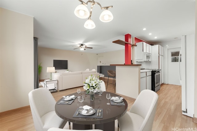 dining space with ceiling fan with notable chandelier and light hardwood / wood-style floors