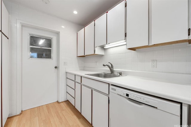 kitchen featuring decorative backsplash, light wood-style floors, light countertops, white dishwasher, and a sink