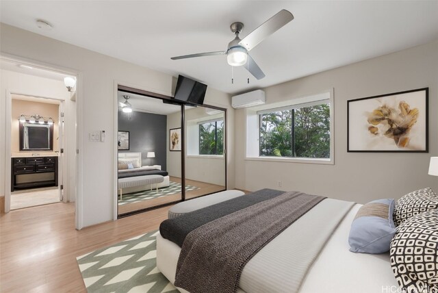 bedroom with ceiling fan, a closet, a wall unit AC, and light hardwood / wood-style flooring