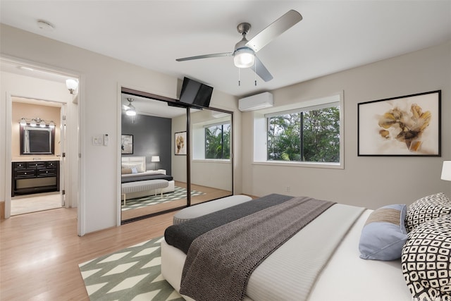 bedroom featuring a closet, a ceiling fan, a wall unit AC, and light wood-style floors