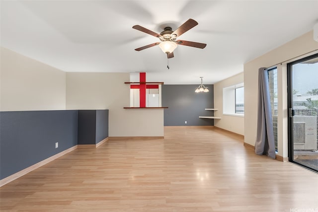 unfurnished living room with light wood-style floors, baseboards, and ceiling fan with notable chandelier