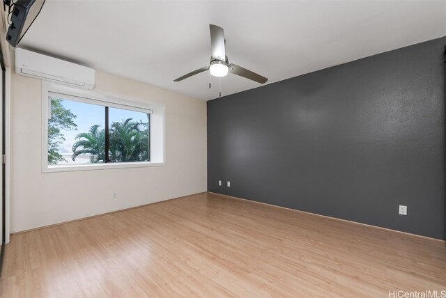 spare room featuring ceiling fan, light hardwood / wood-style floors, and an AC wall unit