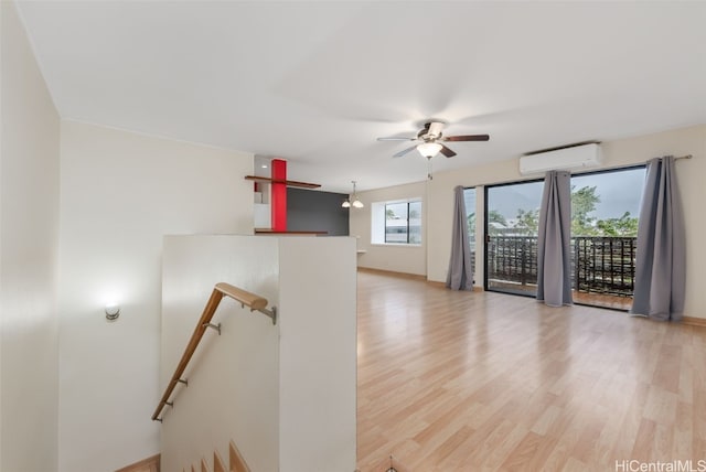 unfurnished room featuring ceiling fan, a wall unit AC, and light hardwood / wood-style flooring