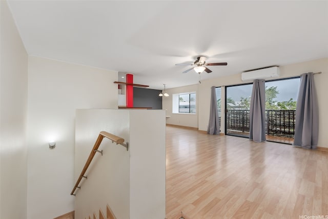 empty room with a ceiling fan, light wood finished floors, and an AC wall unit