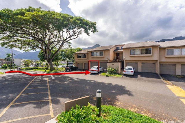 view of property with stucco siding, a mountain view, and driveway