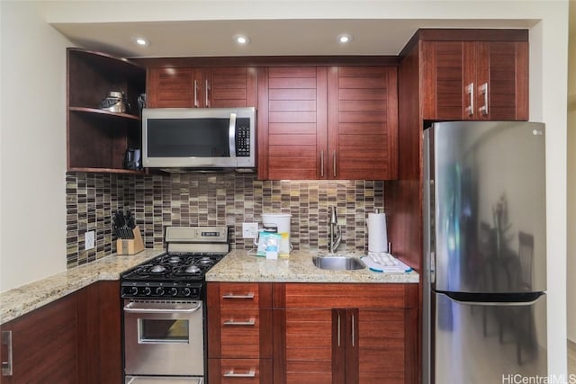 kitchen with tasteful backsplash, appliances with stainless steel finishes, light stone countertops, and sink