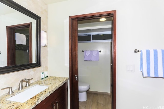 bathroom with toilet, wood-type flooring, vanity, and decorative backsplash