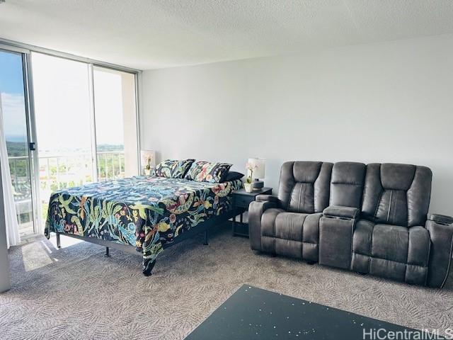 bedroom featuring carpet flooring, a textured ceiling, and a wall of windows