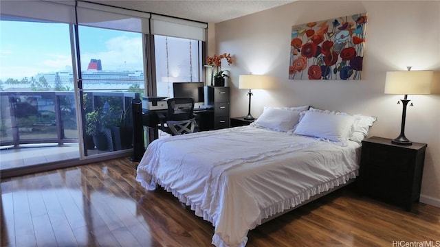 bedroom featuring dark wood-type flooring, a textured ceiling, and a wall of windows