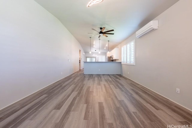 unfurnished living room with ceiling fan, a wall unit AC, and light hardwood / wood-style flooring