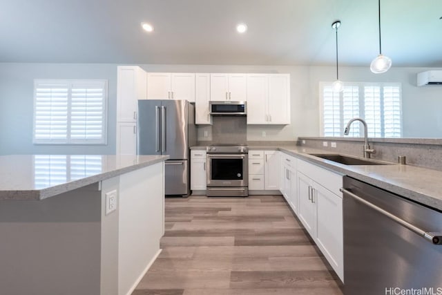 kitchen with high quality appliances, sink, pendant lighting, and white cabinets