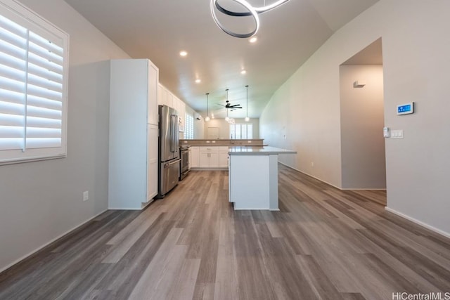 kitchen with high end fridge, white cabinetry, wood-type flooring, a kitchen island, and pendant lighting