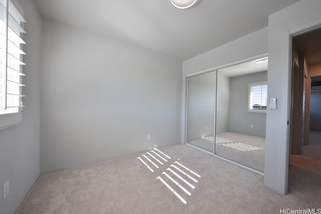 unfurnished bedroom with light colored carpet and a closet