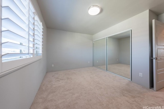 unfurnished bedroom with light colored carpet and a closet