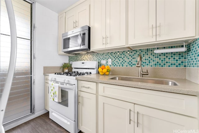 kitchen with sink, tasteful backsplash, white cabinets, dark hardwood / wood-style flooring, and white gas stove